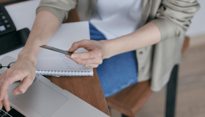 Empreendedora, em seu ao seu notebook, utilizando um cartão, após abrir conta pj com cartão de crédito. | Foto: Mikhail Nilov/Pexels.