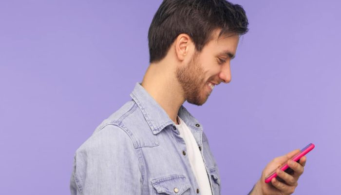 homem olhando para o celular acessando o aplicativo do banco Cora