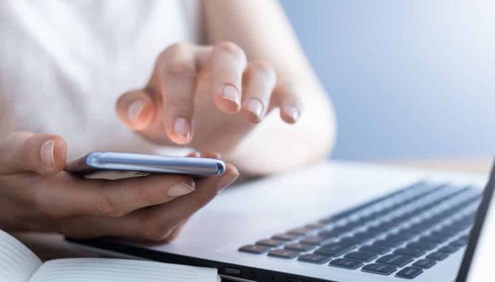 mulher ao celular consultando a lista de códigos dos bancos