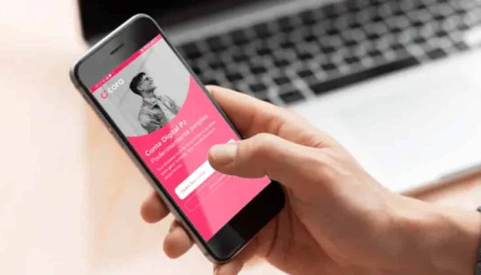 Mão masculina segurando o celular com o aplicativo da conta Cora aberto