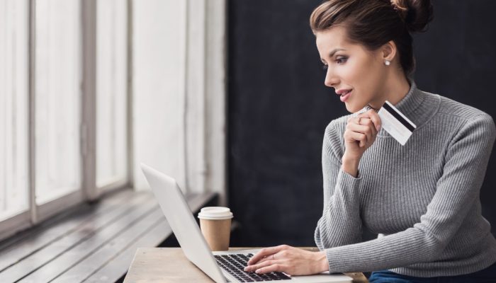 mulher empreendedora olhando para o computador com um cartão de crédito na mão