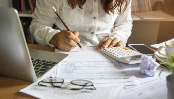 mulher empreendedora estudando o que é iss e fazendo os cálculos da sua empresa