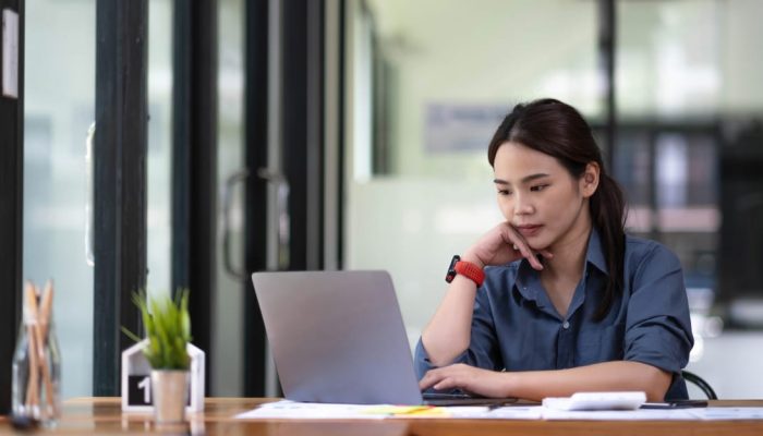 mulher sentada olhando para o computador e consultando o seu score